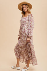 woman wearing a long floral maxi dress with puff sleeves and a straw hat, standing on a light background
