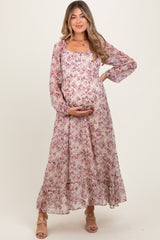 woman wearing a purple floral long sleeve maternity dress and holding her baby bump
