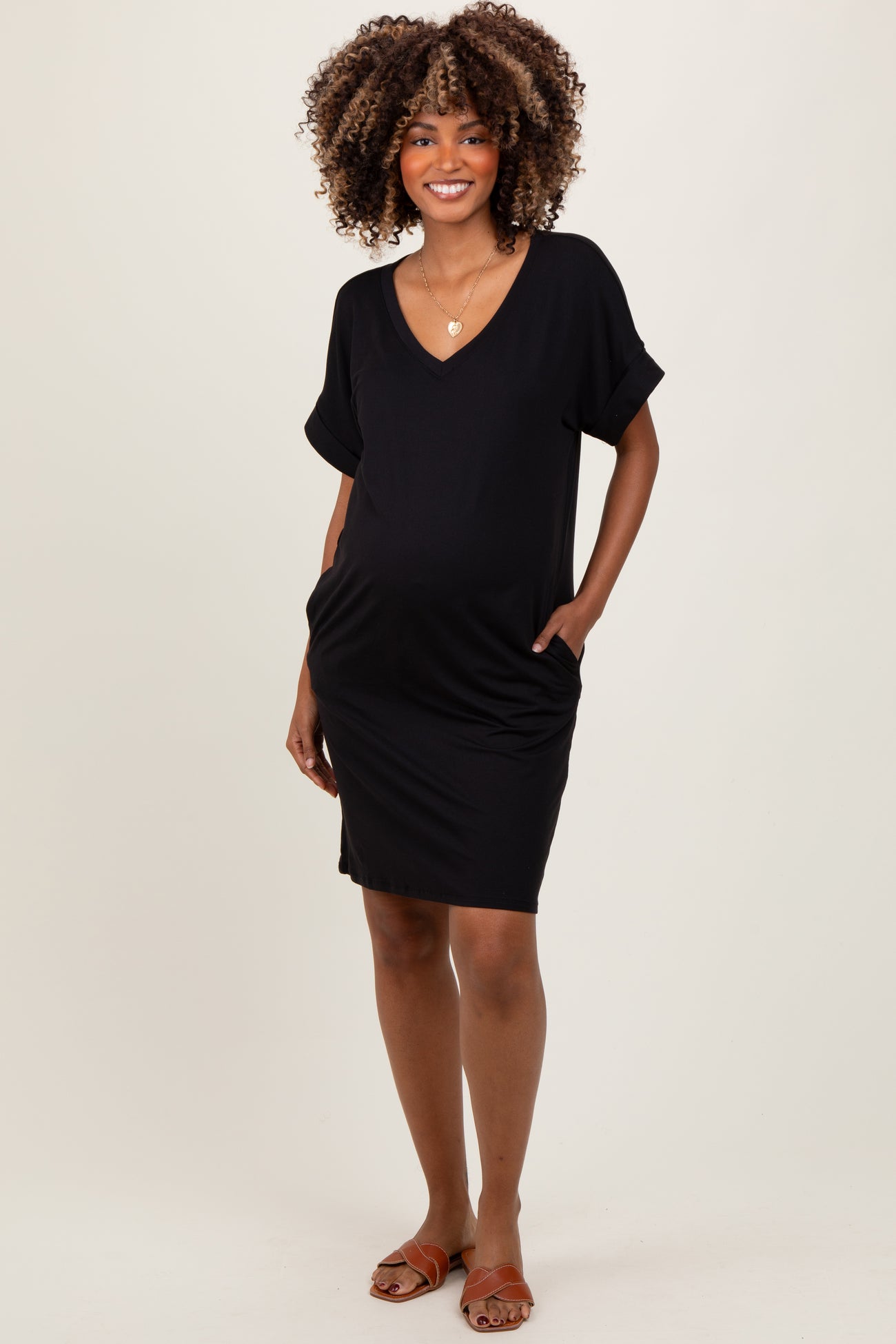 woman wearing a black short sleeve maternity dress with pockets and a visible baby bump