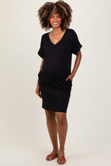 woman wearing a black short sleeve maternity dress with pockets and a visible baby bump