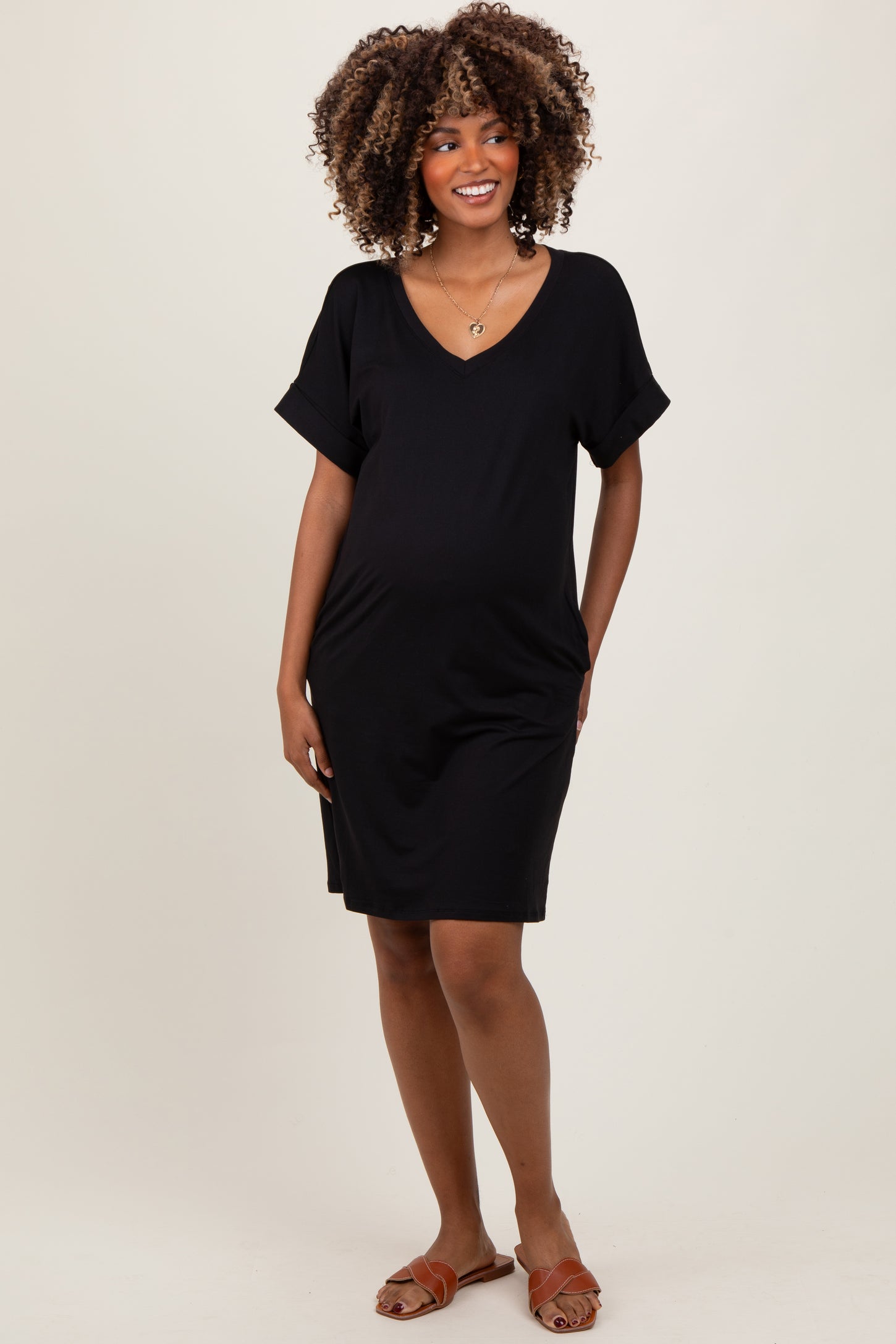 woman wearing a black short sleeve maternity dress with a v-neck and pockets, showcasing her baby bump