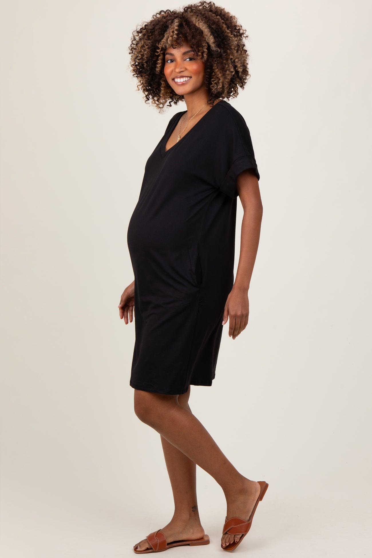 woman wearing a black short sleeve maternity dress with side pockets and a visible baby bump