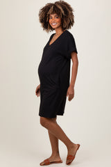 woman wearing a black short sleeve maternity dress with side pockets and a visible baby bump