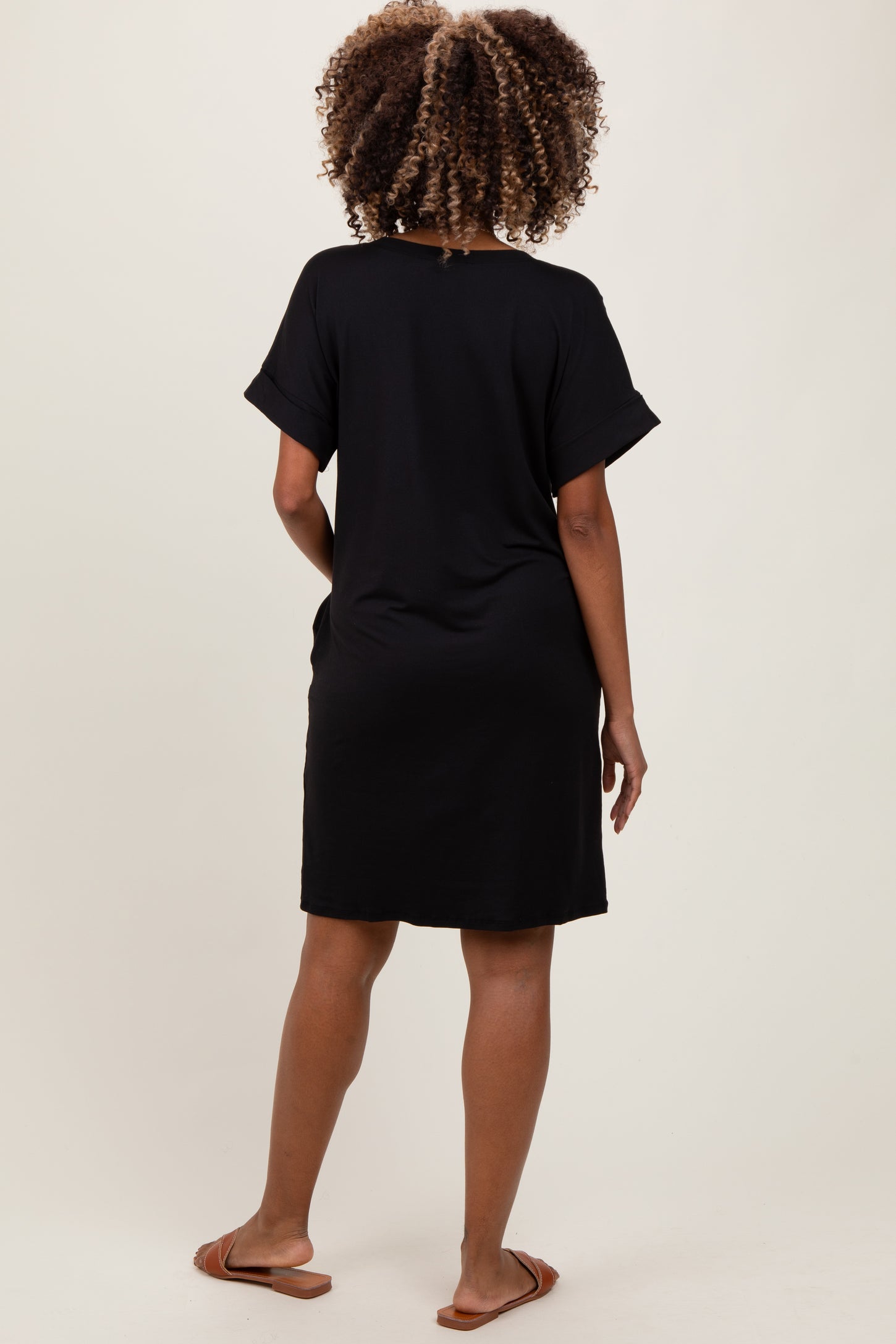 woman wearing a black short sleeve maternity dress, showing a relaxed fit from the back