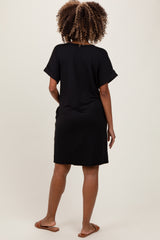 woman wearing a black short sleeve maternity dress, showing a relaxed fit from the back