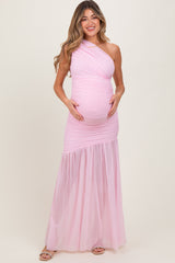 woman wearing a light pink one-shoulder maternity gown with ruched detailing and a flowing skirt, showcasing her baby bump