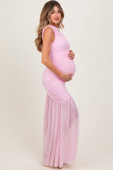 woman wearing a light pink maternity gown with ruched detailing and a flowing skirt, showcasing her baby bump