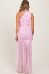 woman wearing a light pink one-shoulder maternity gown with a fitted bodice and flowing skirt