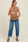 woman wearing a brown ribbed maternity tank top and blue relaxed fit jeans, holding her baby bump