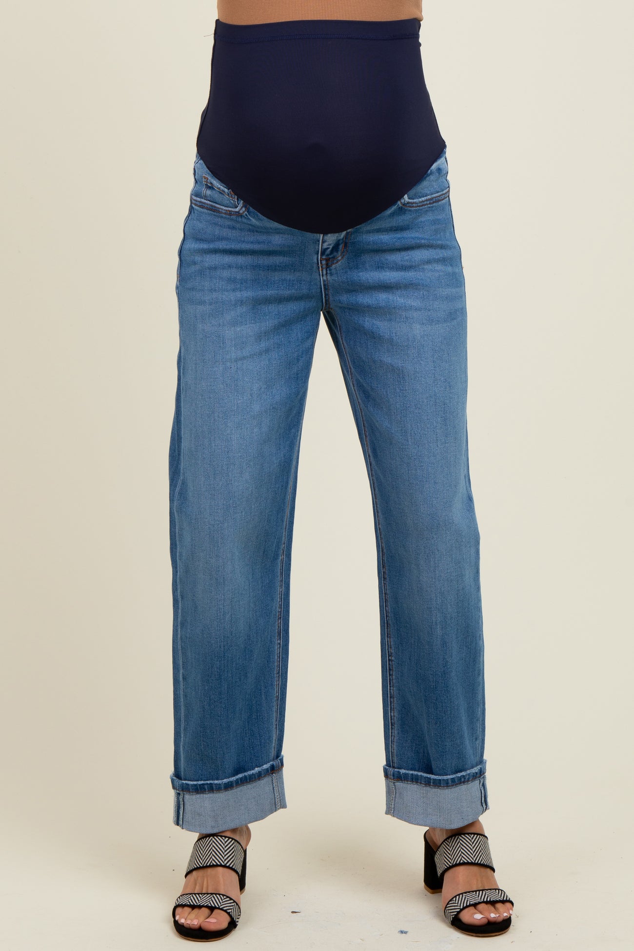 woman wearing a pair of light blue maternity jeans with a dark blue over-the-bump waistband and cuffed hems
