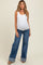 woman wearing a white ribbed maternity tank top and blue wide-leg maternity jeans with a visible baby bump