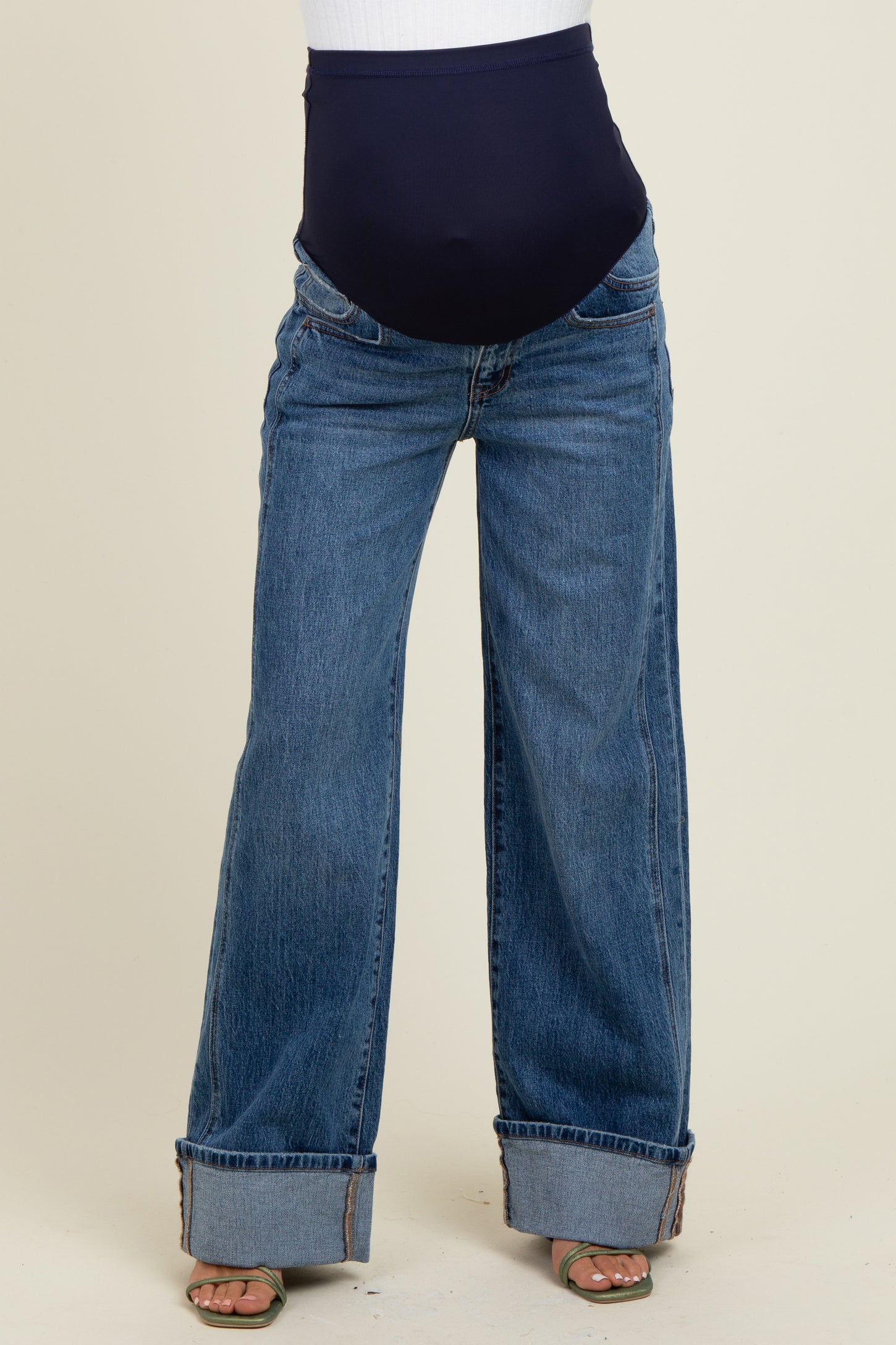 woman wearing blue wide-leg maternity jeans with a high waistband and cuffed hems, showing a pregnant belly