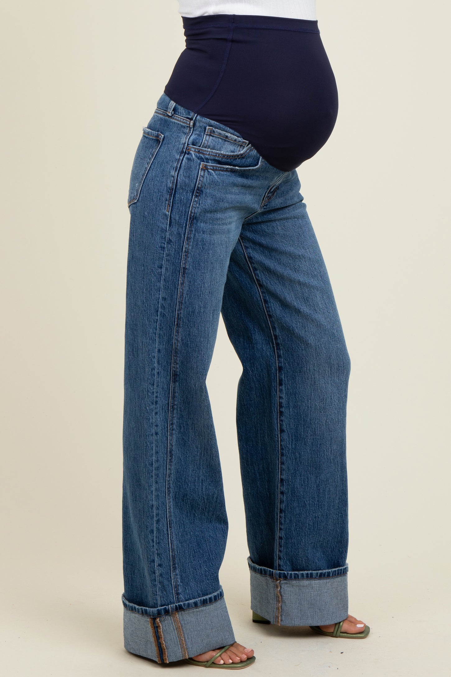 woman wearing a navy blue maternity belly band with wide-leg blue jeans and a visible baby bump