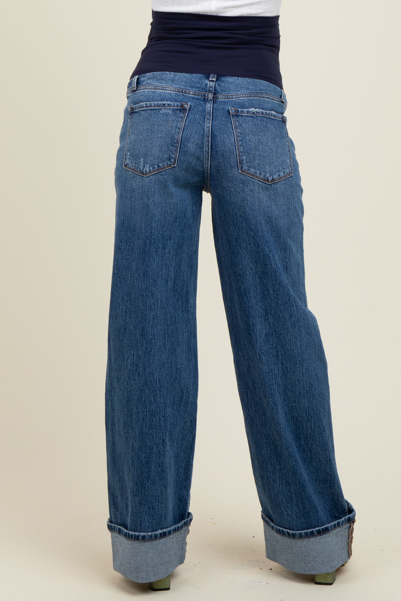 woman wearing light blue maternity jeans with a wide leg and folded cuffs, showcasing a stretchy black waist panel