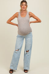 woman wearing a beige ribbed maternity tank top and distressed light blue jeans, showing her baby bump.