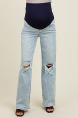 woman wearing light blue distressed maternity jeans with a navy blue over-the-bump waistband and no visible baby bump