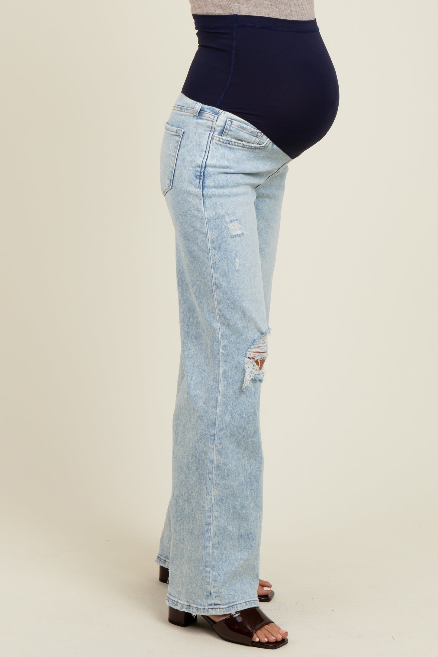 maternity wear light blue distressed flared jeans with a navy blue over-the-bump panel and a visible baby bump