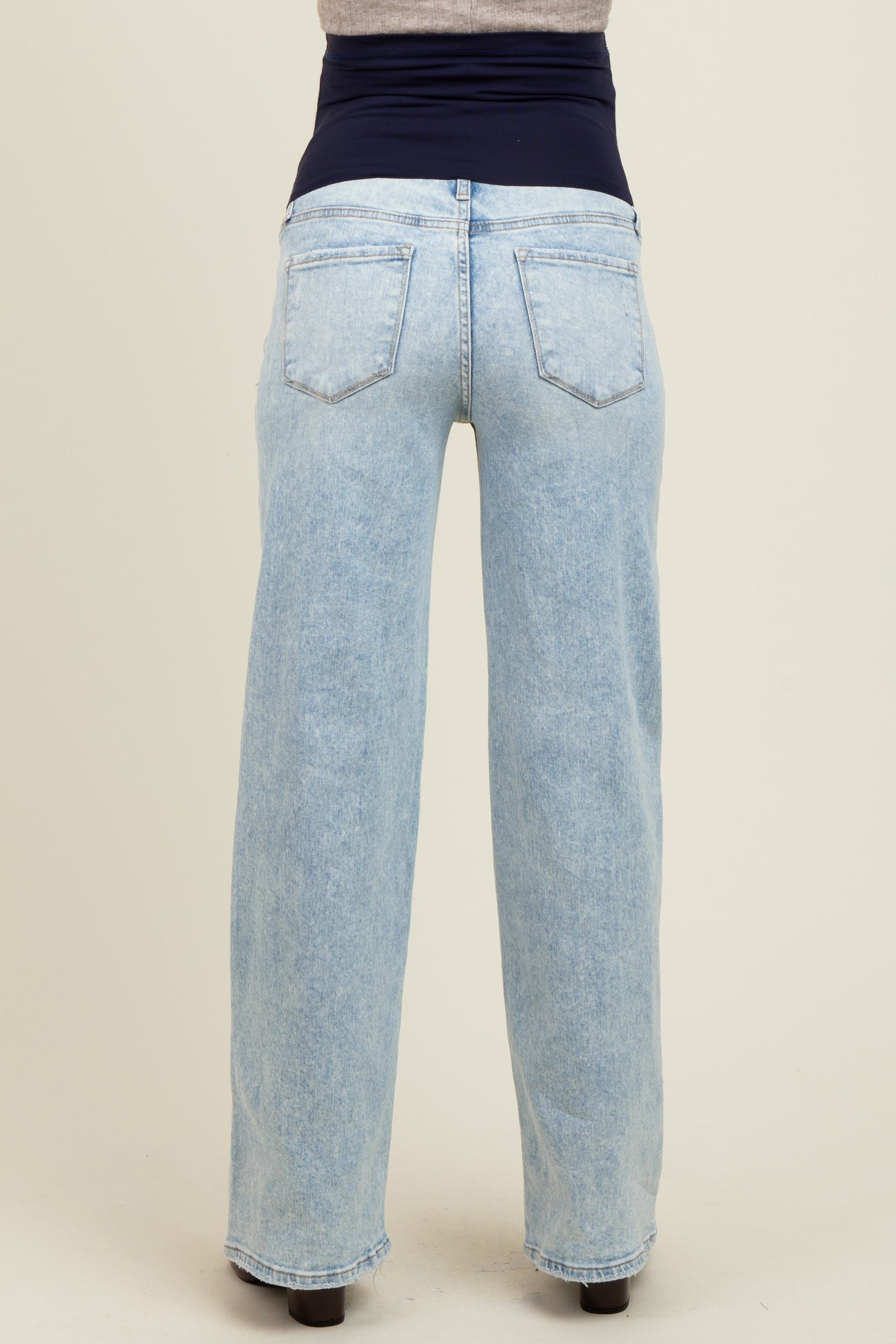 woman wearing light blue maternity jeans with a wide waistband, viewed from the back