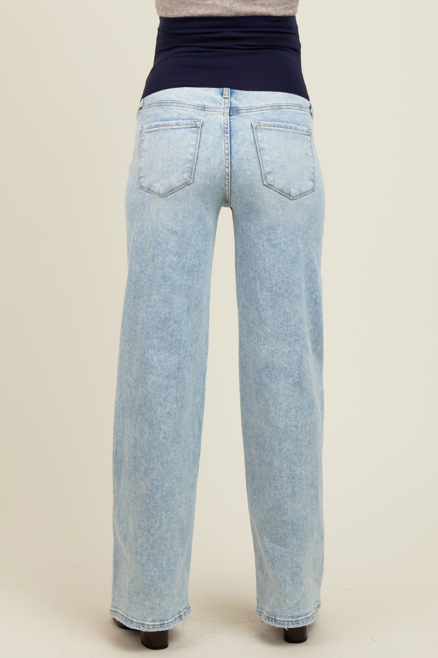 woman wearing light blue maternity jeans with a wide waistband, viewed from the back
