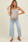 woman wearing a beige ribbed maternity tank top and light blue wide-leg jeans, showing her baby bump