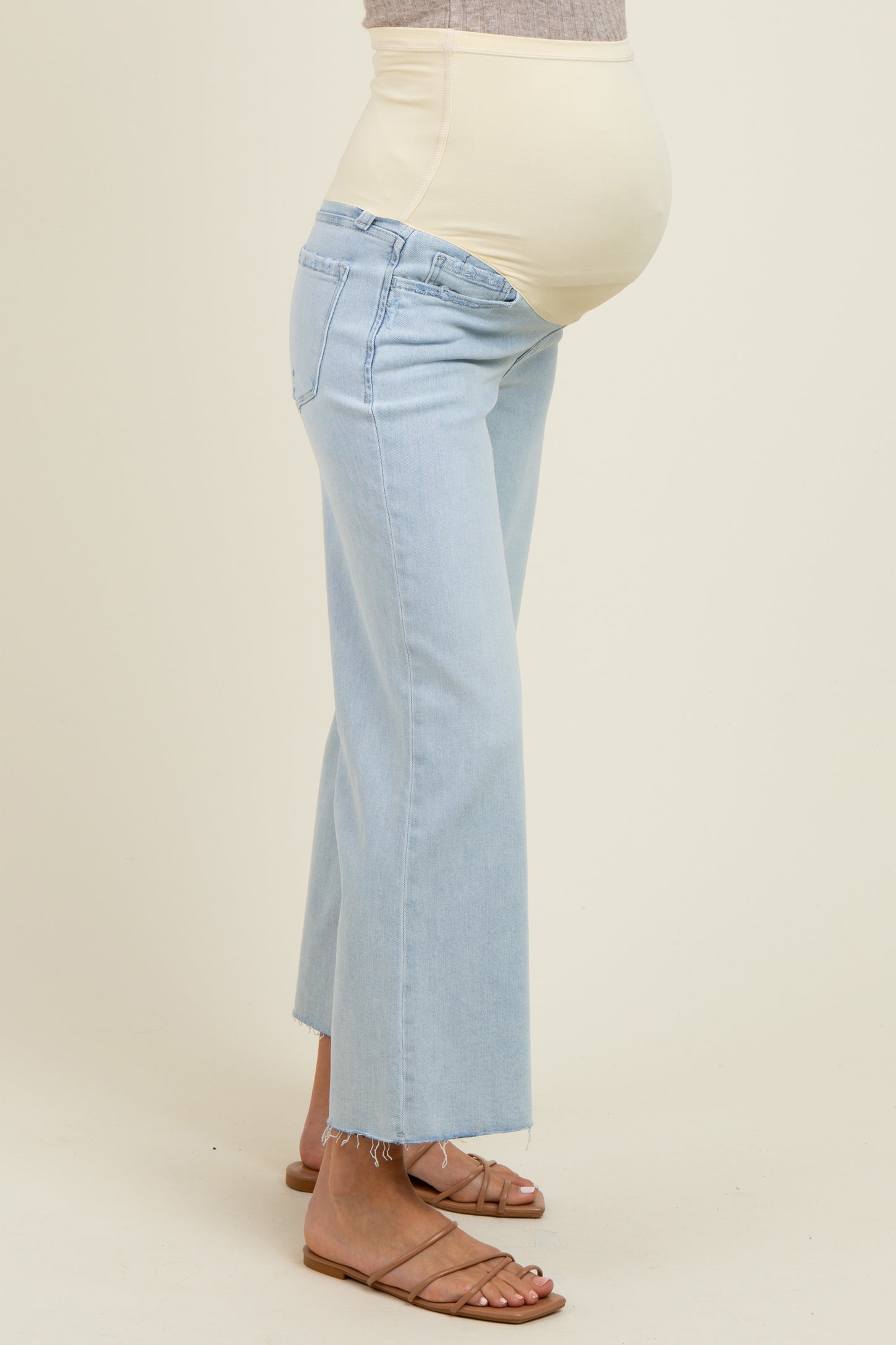 woman wearing light blue maternity jeans with a fitted waistband and a visible baby bump