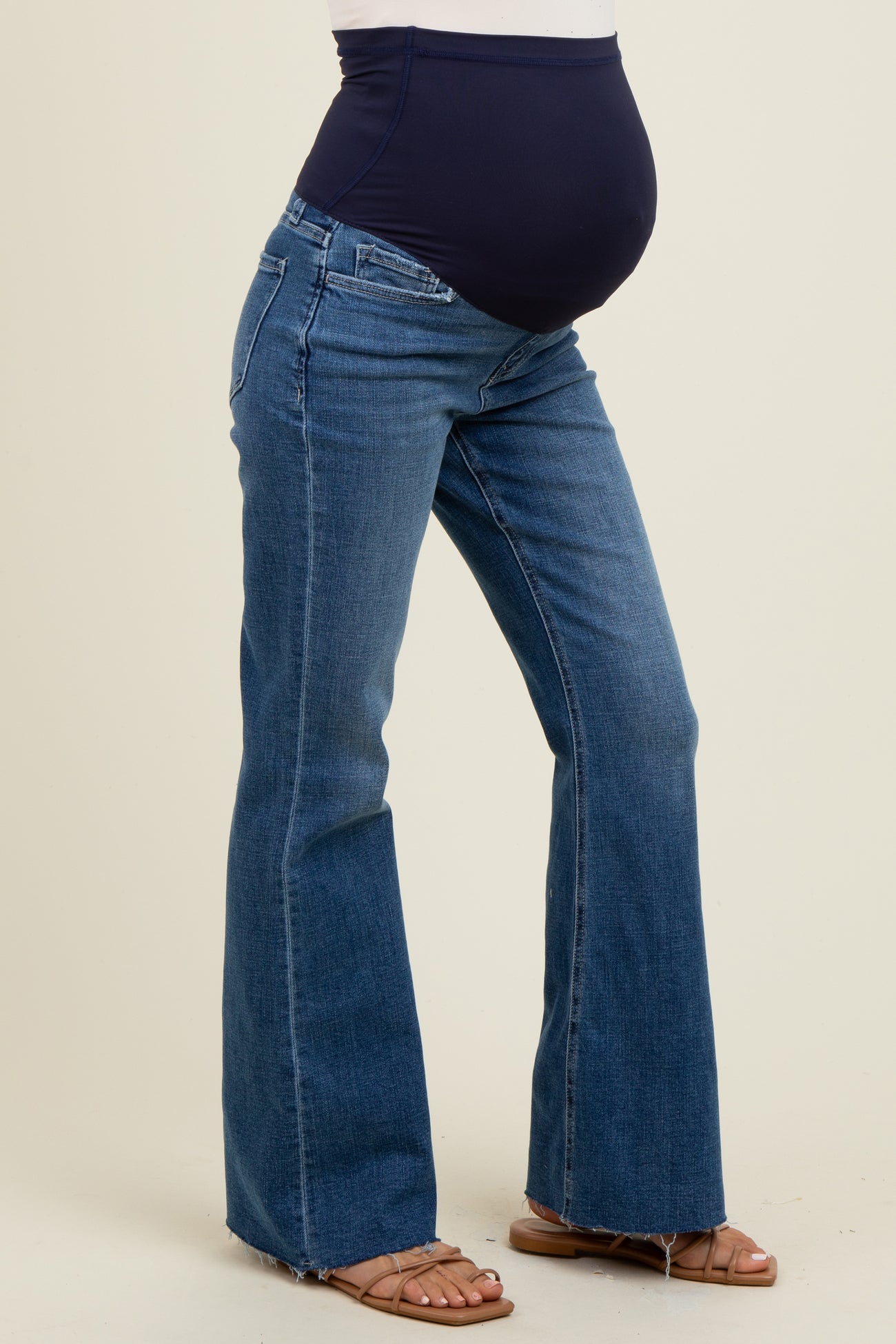 woman wearing a navy blue maternity belly band with flared blue maternity jeans and a visible baby bump