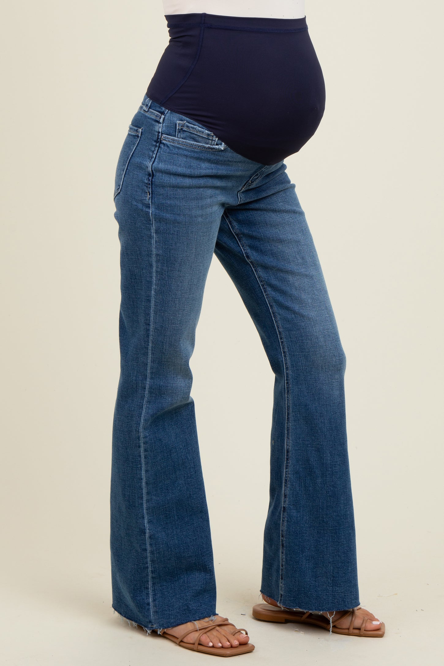 woman wearing a navy blue maternity belly band with flared blue maternity jeans and a visible baby bump