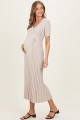 woman wearing a beige ribbed maternity dress with a v-neckline and a tie waist, showcasing her baby bump
