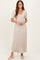 woman wearing a light beige pleated maxi dress with short sleeves and a tie waist detail