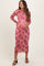 woman wearing a sheer pink floral maternity dress and holding her baby bump