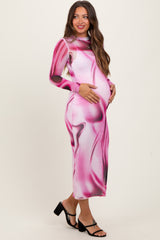 woman wearing a pink and black abstract print maternity dress with long sleeves and a visible baby bump