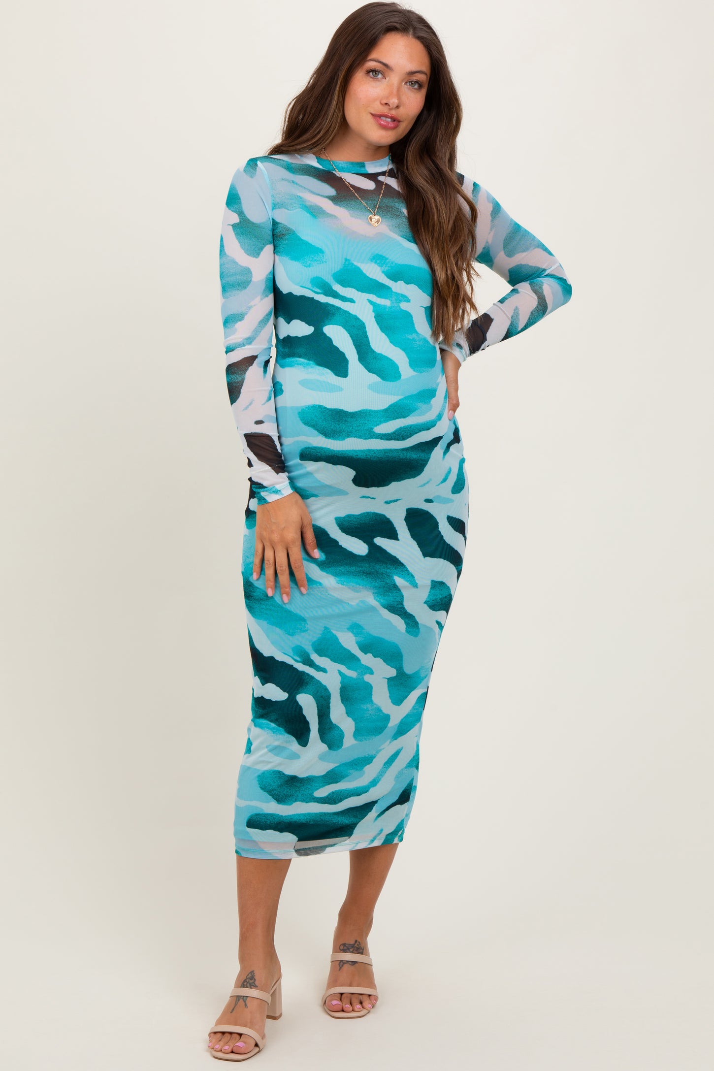 woman wearing a turquoise camo print long sleeve maternity dress, showcasing her baby bump
