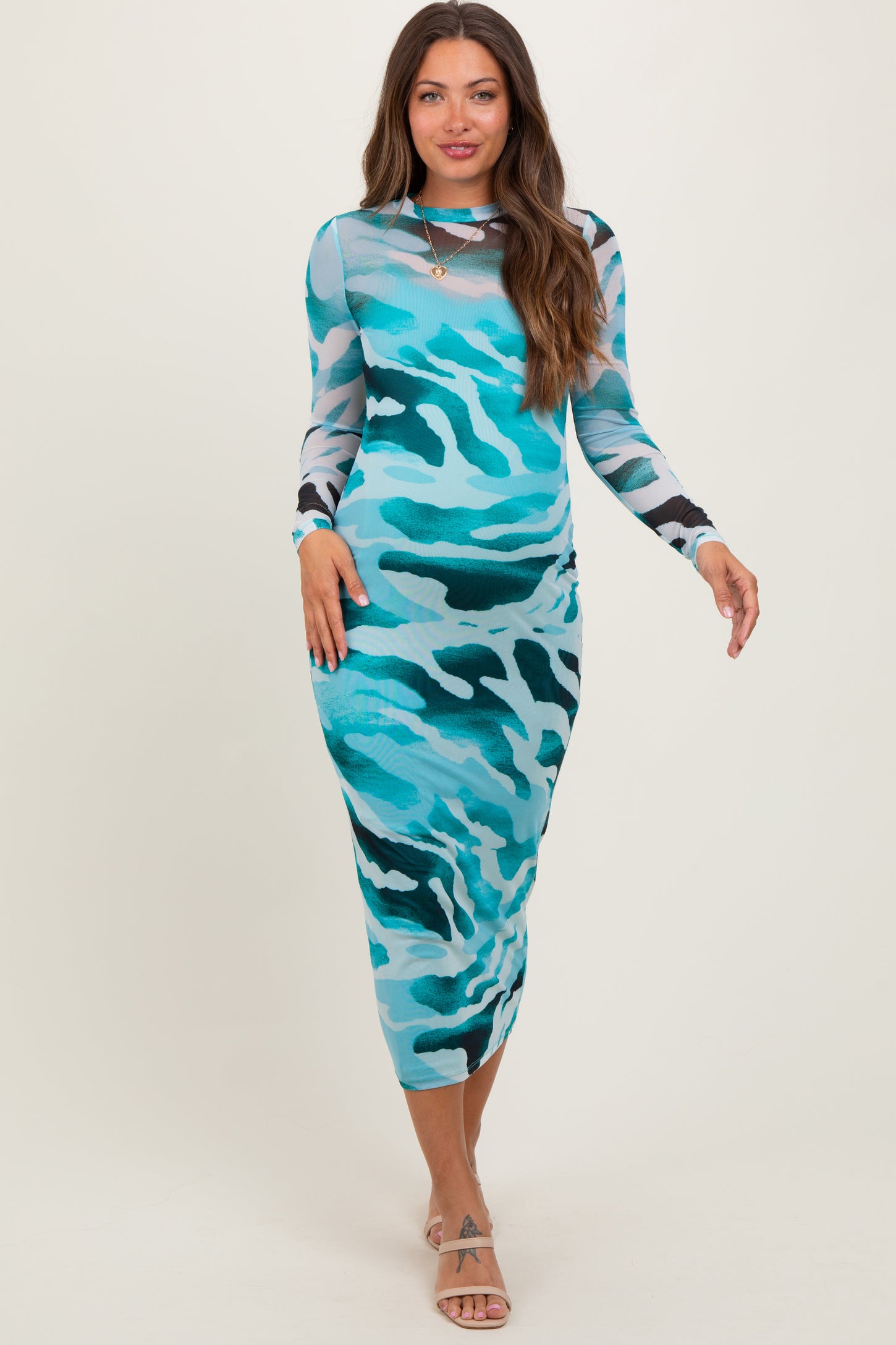 woman wearing a blue camouflage print maternity dress with long sleeves and a fitted silhouette, showcasing her baby bump