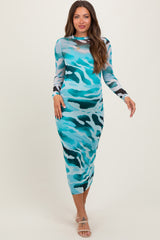 woman wearing a blue camouflage print maternity dress with long sleeves and a fitted silhouette, showcasing her baby bump