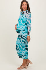 woman wearing a turquoise and black striped maternity dress, highlighting her baby bump