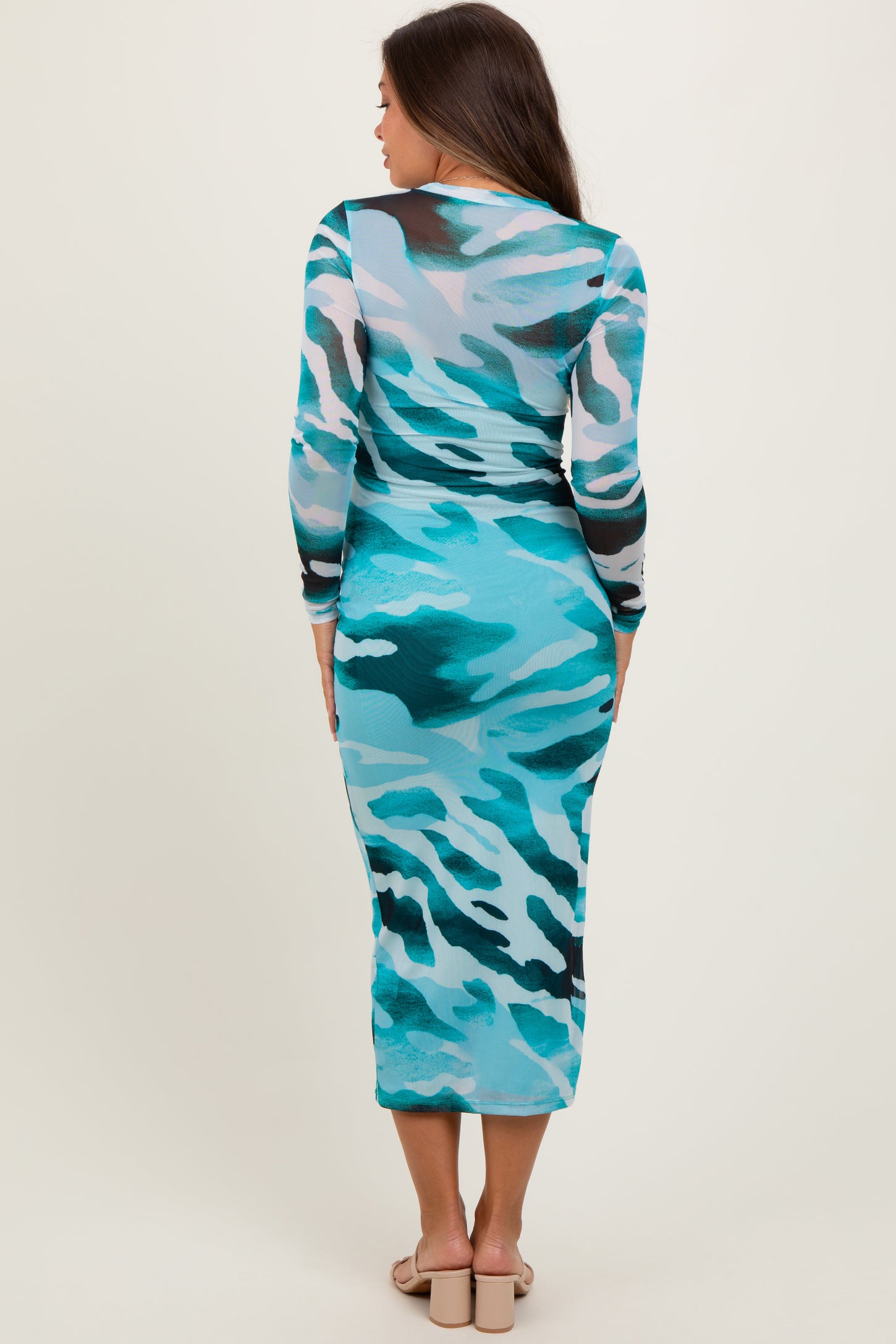 woman wearing a turquoise camouflage print long sleeve maternity dress, showcasing a fitted silhouette from the back