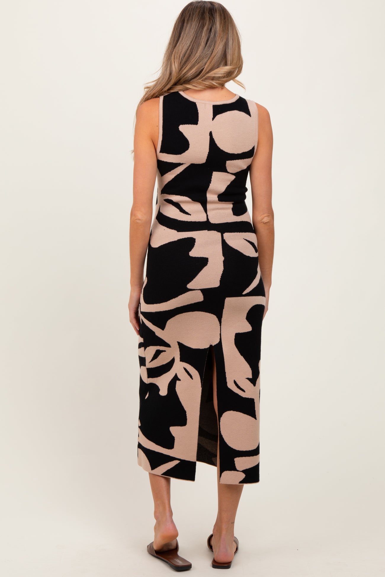 woman wearing a black and tan abstract patterned maternity dress with a back slit