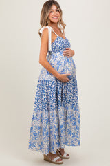 woman wearing a blue and white floral print maternity maxi dress holding her baby bump
