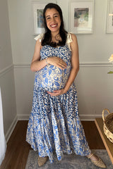 woman wearing a blue and white patterned maternity dress and holding her baby bump
