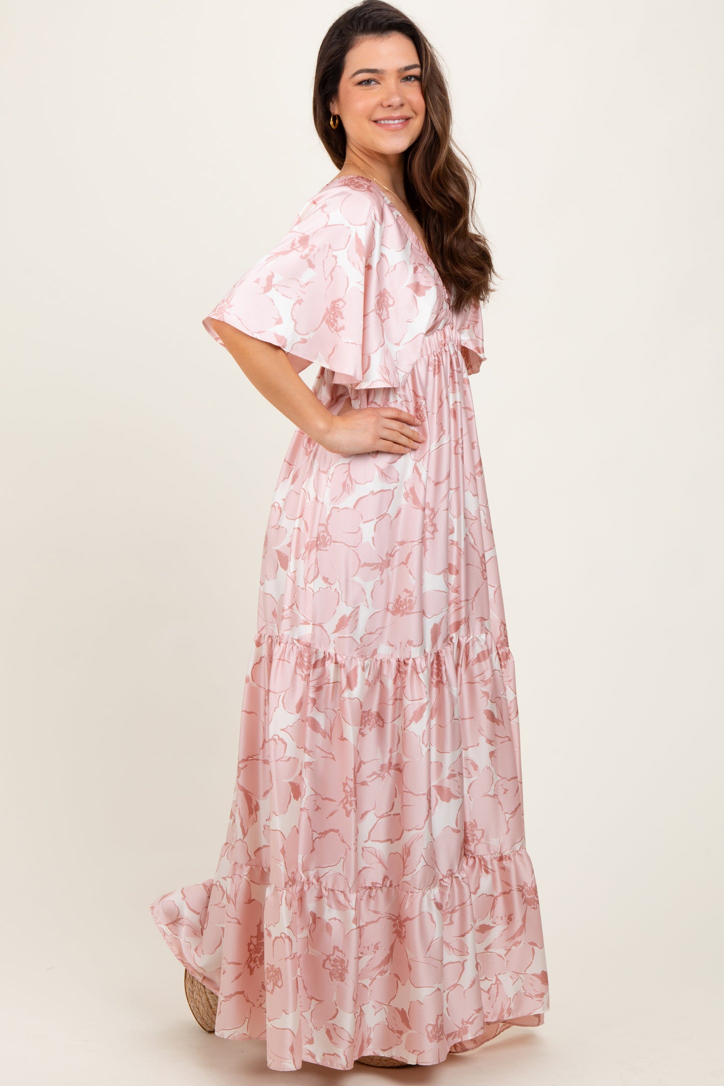 woman wearing a pink floral maxi dress with ruffled sleeves and tiered hem