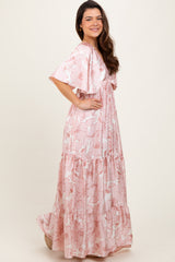 woman wearing a pink floral maxi dress with ruffled sleeves and tiered hem