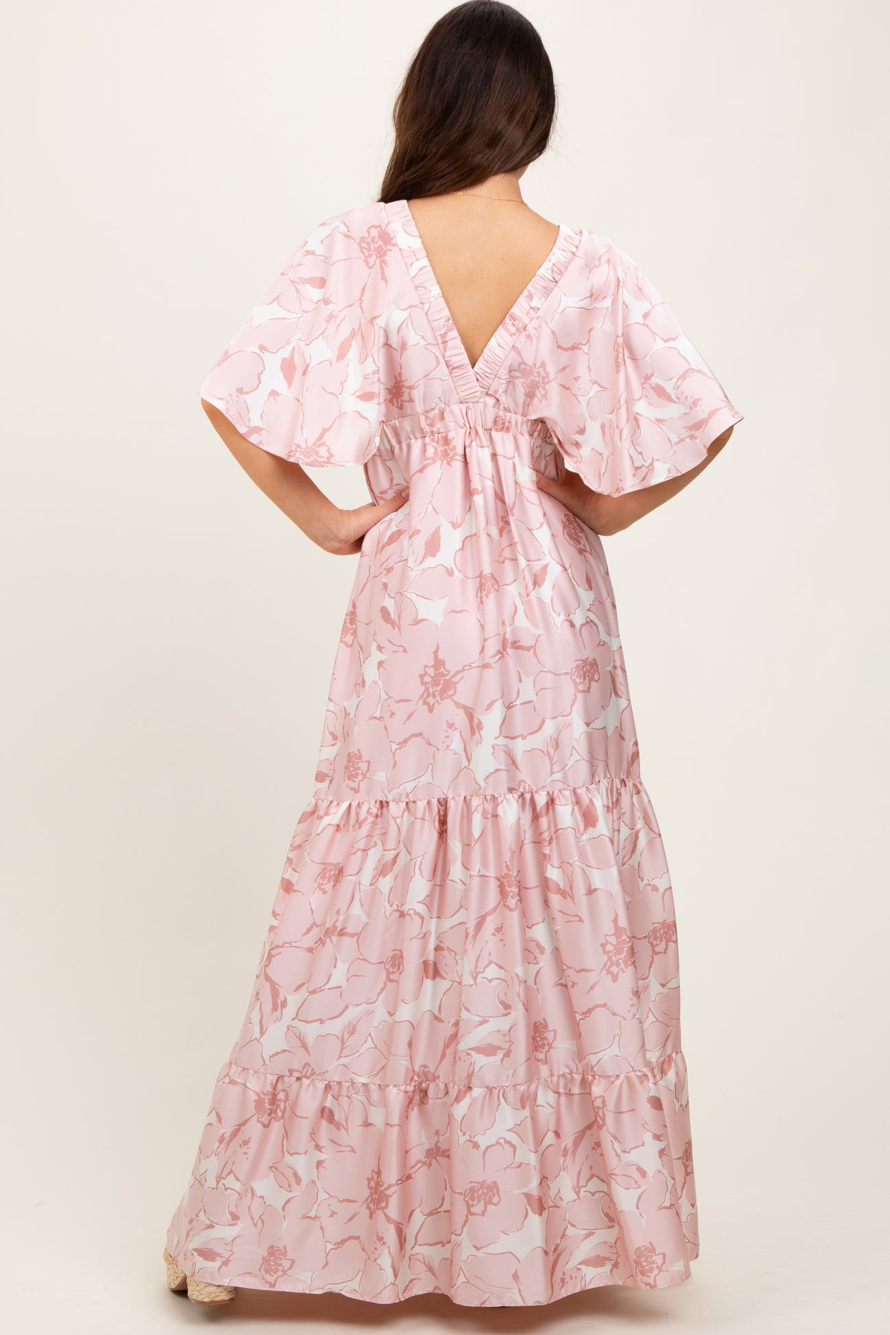 woman wearing a pink floral maxi dress with flutter sleeves and a low back view