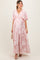 woman wearing a pink floral maternity maxi dress with ruffle sleeves and a flowing skirt, showing her baby bump