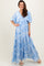woman wearing a light blue floral maxi dress with flutter sleeves and a tiered skirt