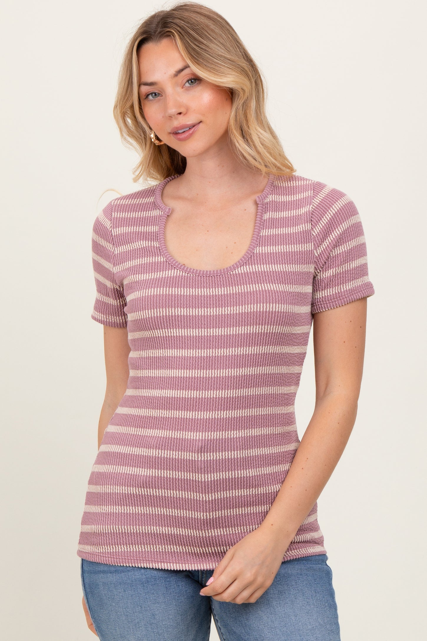 woman wearing a purple and white striped short sleeve top with a scoop neckline and ribbed texture