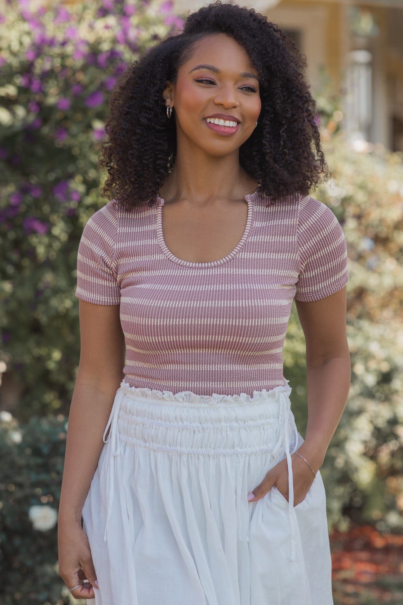 woman wearing a pink and white striped short sleeve top with a scoop neckline and white drawstring skirt