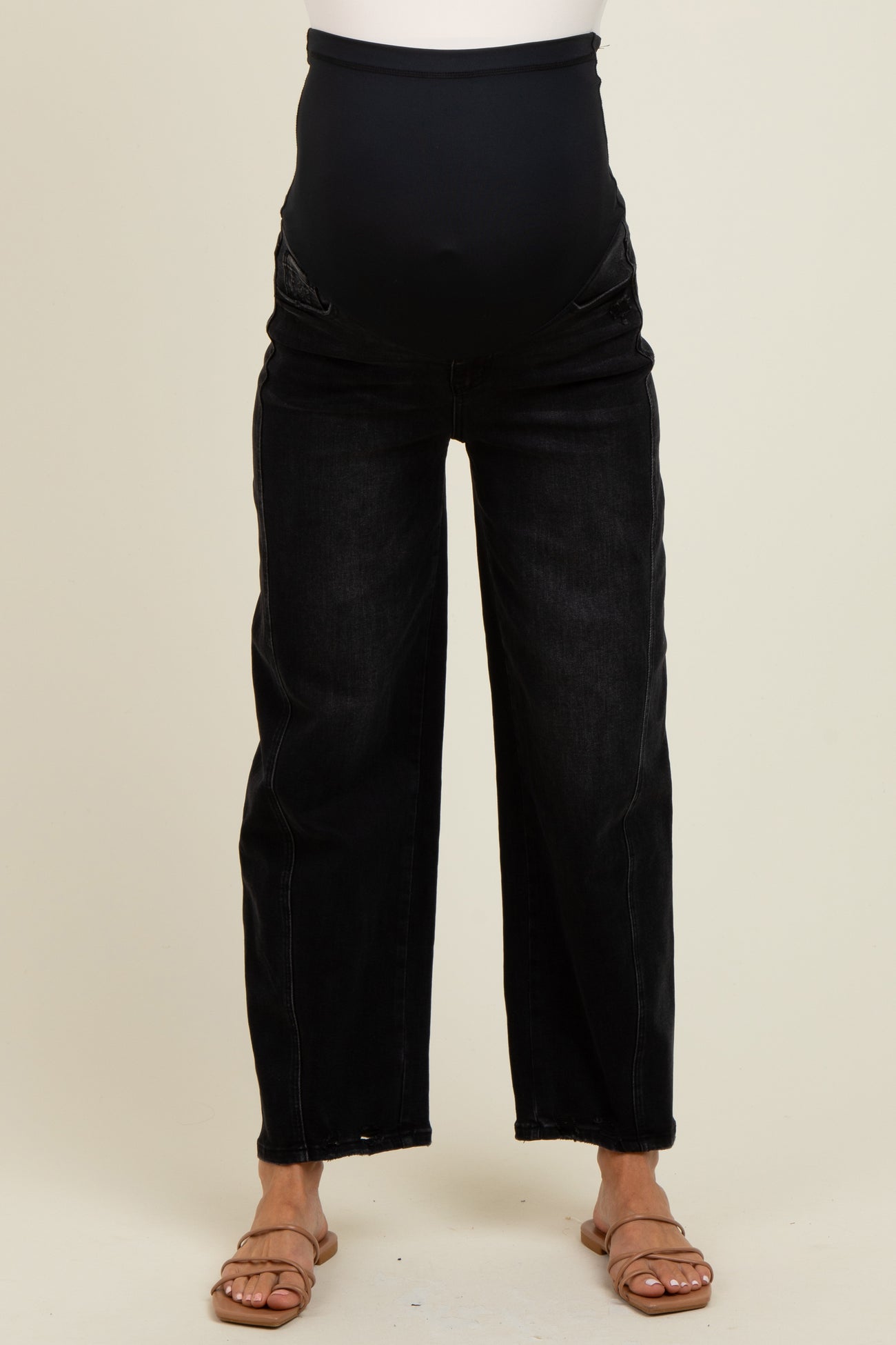 woman wearing black wide leg maternity jeans with a belly panel and a visible baby bump