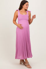 woman wearing a pink maxi maternity dress with tie straps and a visible baby bump
