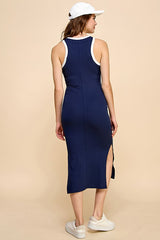 woman wearing a navy blue sleeveless midi dress with side slit and white trim, viewed from the back