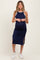 woman wearing a navy blue ribbed maternity dress with white trim and side slits, showcasing her baby bump